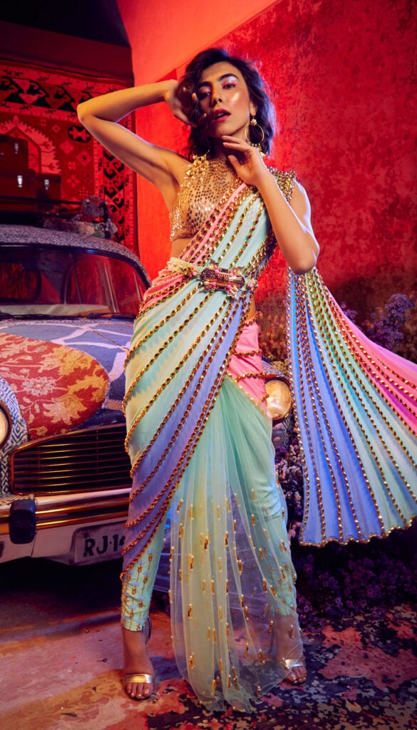 Multicolored pant saree covered with embroidery. It is paired with a contrasting nude halter neck blouse and an embellished belt.