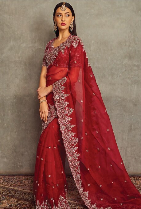 Featuring a red saree in organza base with zardosi embroidery. It is paired with a matching blouse.