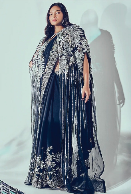 Featuring a navy blue saree in georgette and tulle base with beads and embroidery. It is paired with a matching bralette and a cape having sequins and metallic hand embroidery.