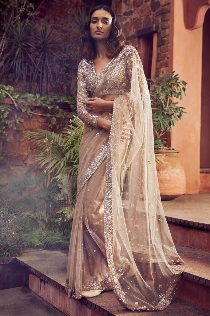 Featuring a coffee brown saree in net base with sequins and swarovski embroidery. It is paired with a matching embellished blouse.