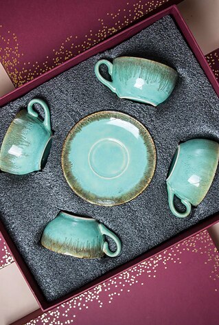 Gift box containing four pastel green cups and saucers.