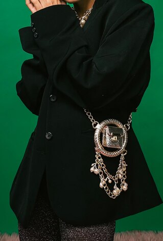 A gold mini crossbody bag in faux leather base with pearl work including chain link hanging details. It has a suede lining.