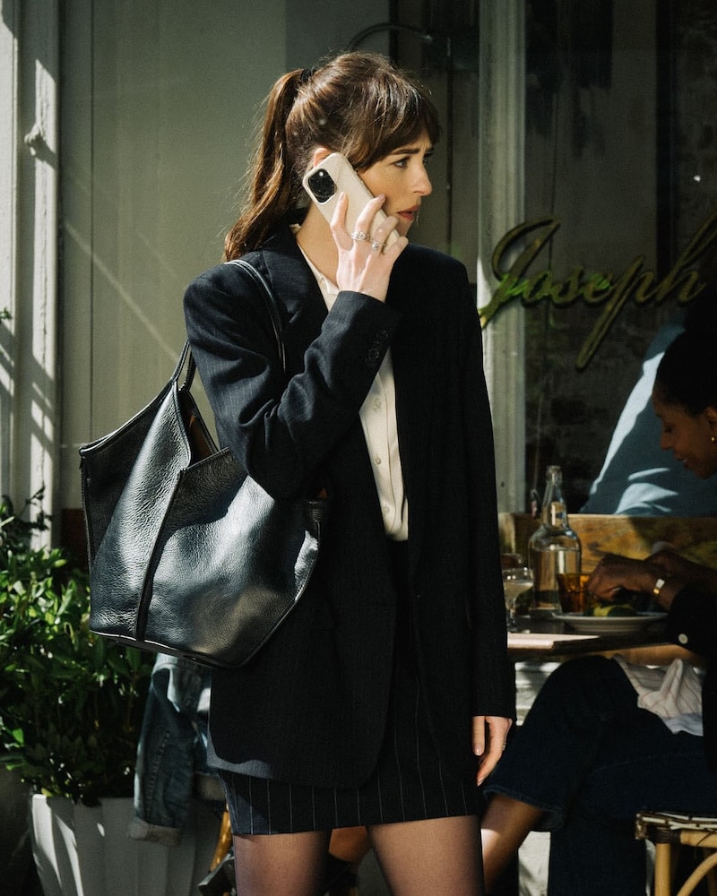 Dakota Johnson Dressed in a pinstripe blazer with a crisp white shirt, bodycon skirt and boots