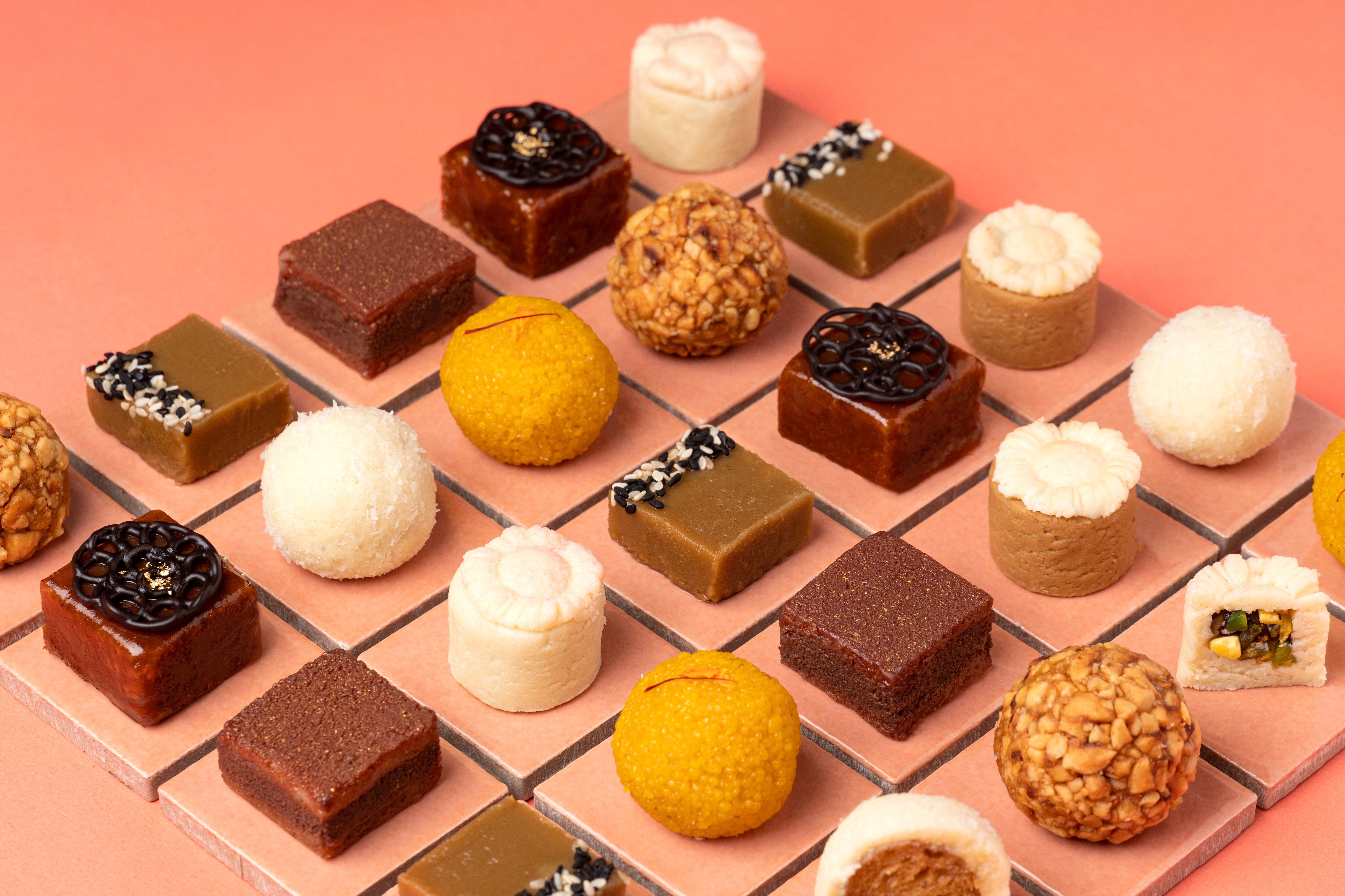 The image displays a beautiful assortment of Indian sweets, commonly known as Mithai